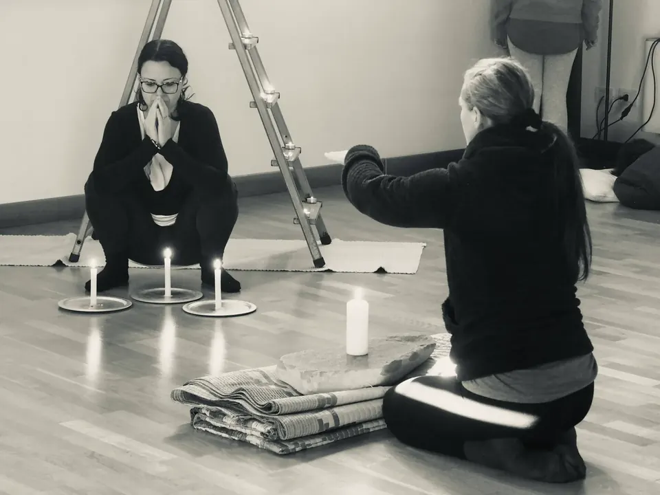 Due persone durante una pratica esperienziale accompagnata dalla luce delle candele